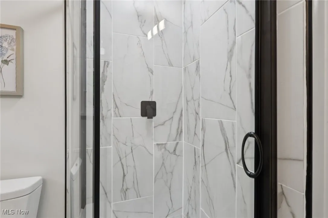 Full bath featuring a marble finish shower