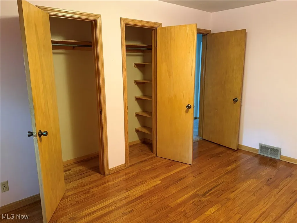 Unfurnished bedroom with multiple closets and light wood-style floors