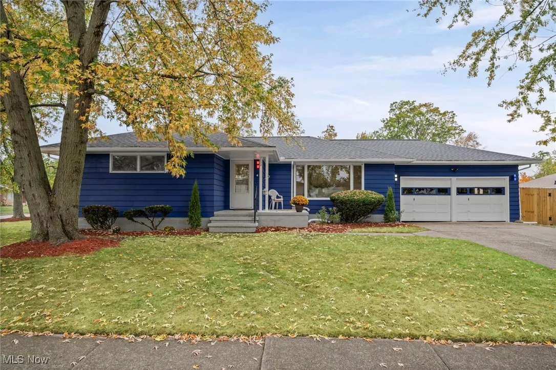 Single story home featuring a front lawn, an attached garage, driveway, and roof with shingles