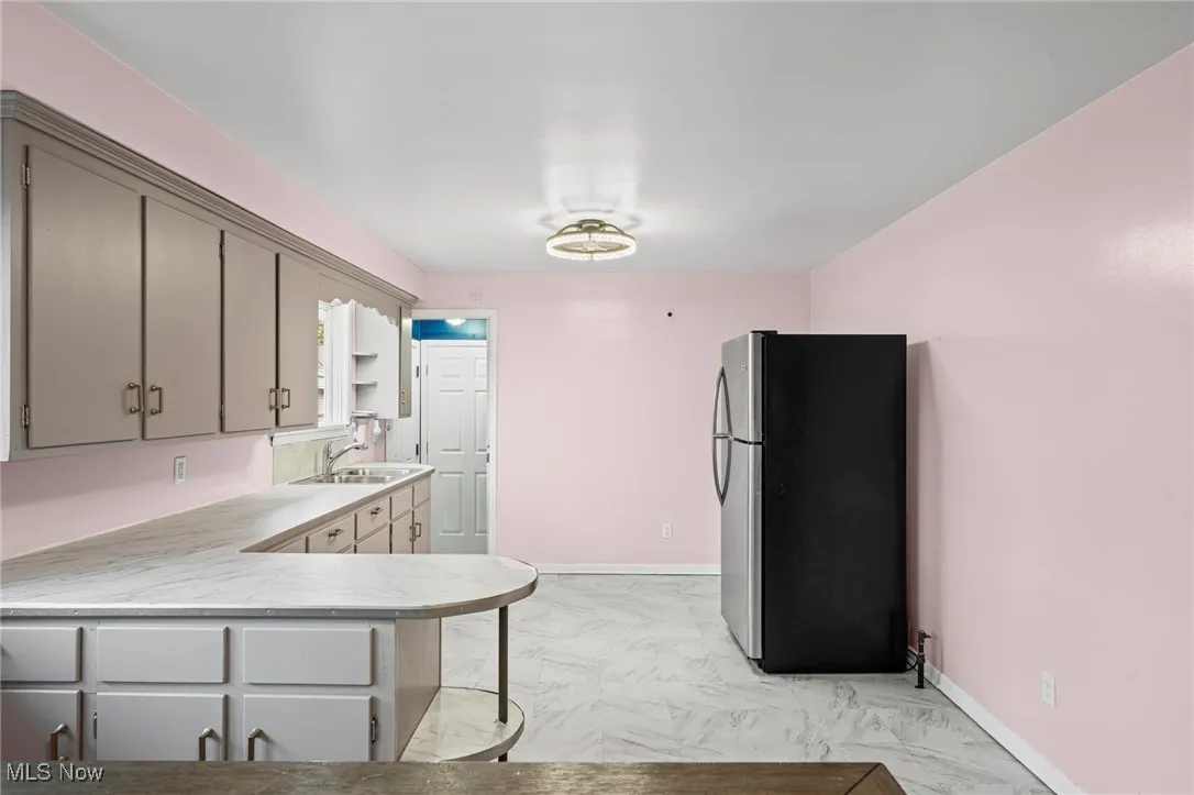 Kitchen featuring light countertops, freestanding refrigerator, a peninsula, and open shelves