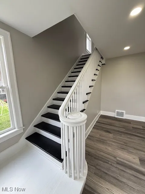Staircase featuring wood finished floors, plenty of natural light, and recessed lighting