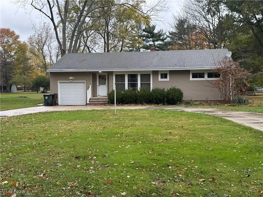 Ranch-style home with driveway, a front yard, a chimney, and a garage