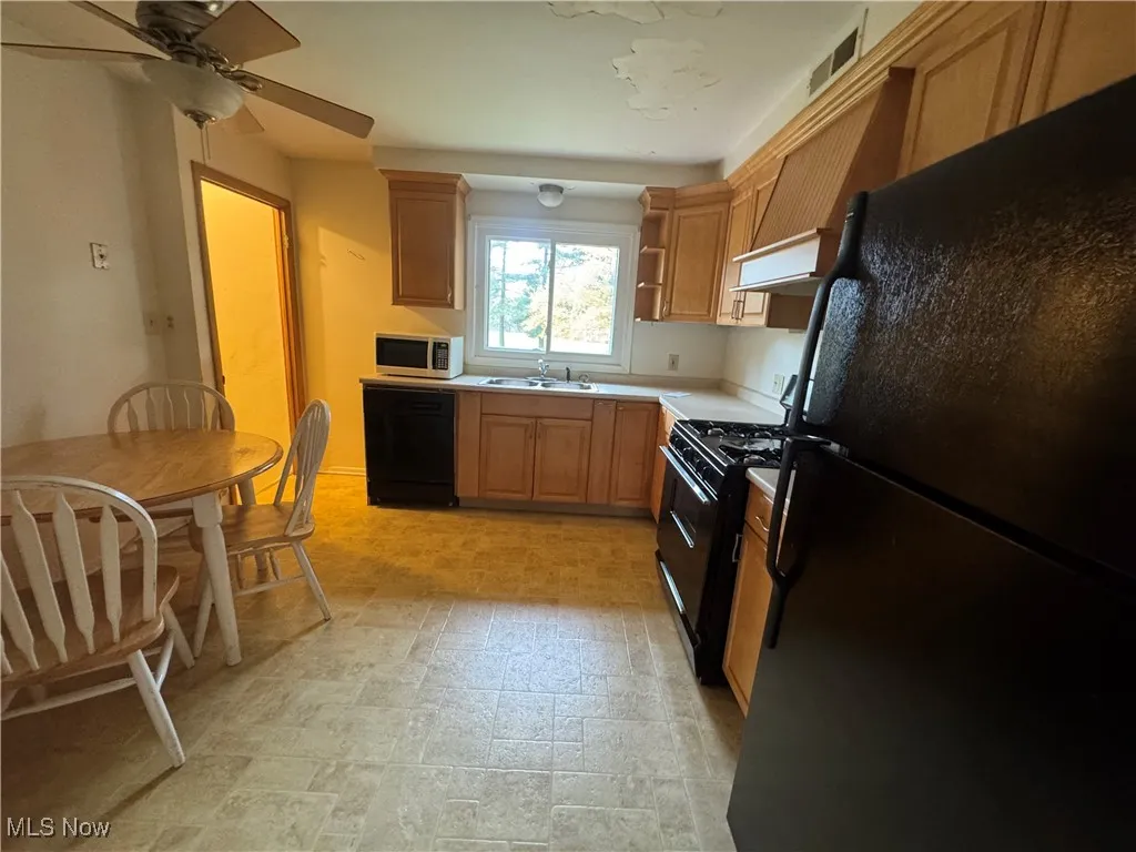 Kitchen featuring black appliances, light countertops, extractor fan, ceiling fan, and open shelves