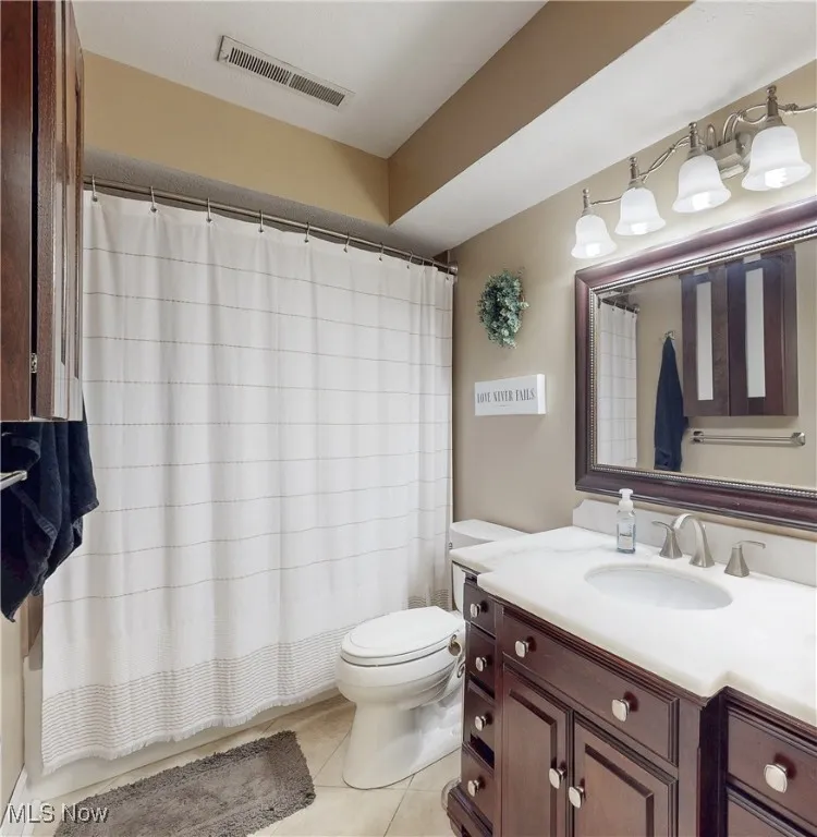 Full bathroom featuring vanity, light tile patterned floors, and shower / bath combo with shower curtain