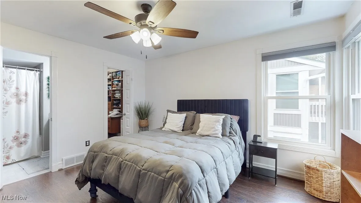 Bedroom featuring wood finished floors, a spacious closet, ceiling fan, and ensuite bathroom