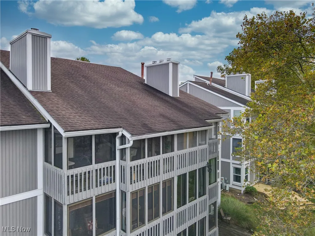 Back of property featuring a sunroom, a chimney, and a shingled roof