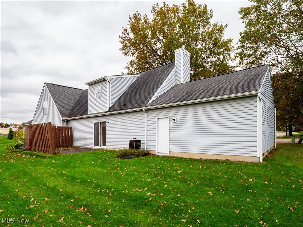 Rear view of property featuring a shingled roof, a yard, and a chimney