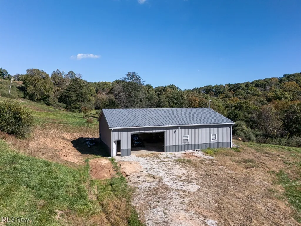 View of pole building featuring a forest view and driveway