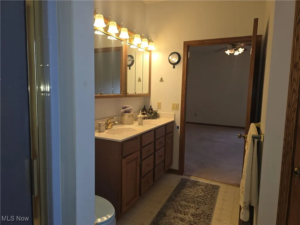 Full bathroom with double vanity and vinyl flooring. Separate shower stall and linen closet.
