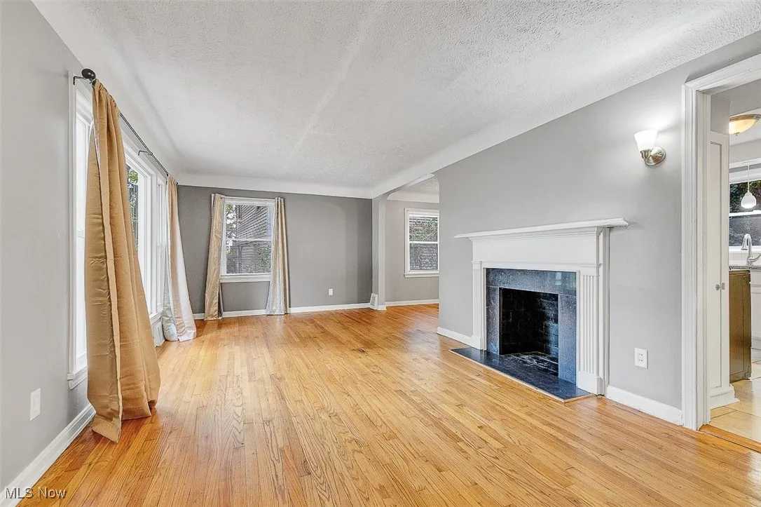 Unfurnished living room featuring light wood-style flooring, a textured ceiling, and a fireplace