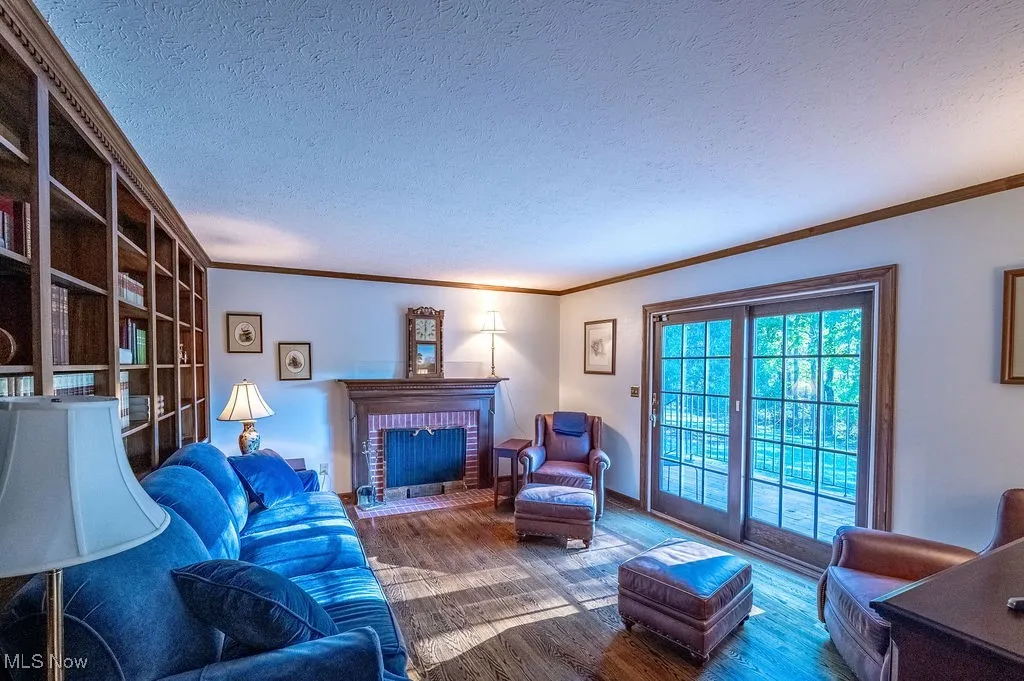 Living room featuring a textured ceiling, crown molding, wood finished floors, and a fireplace