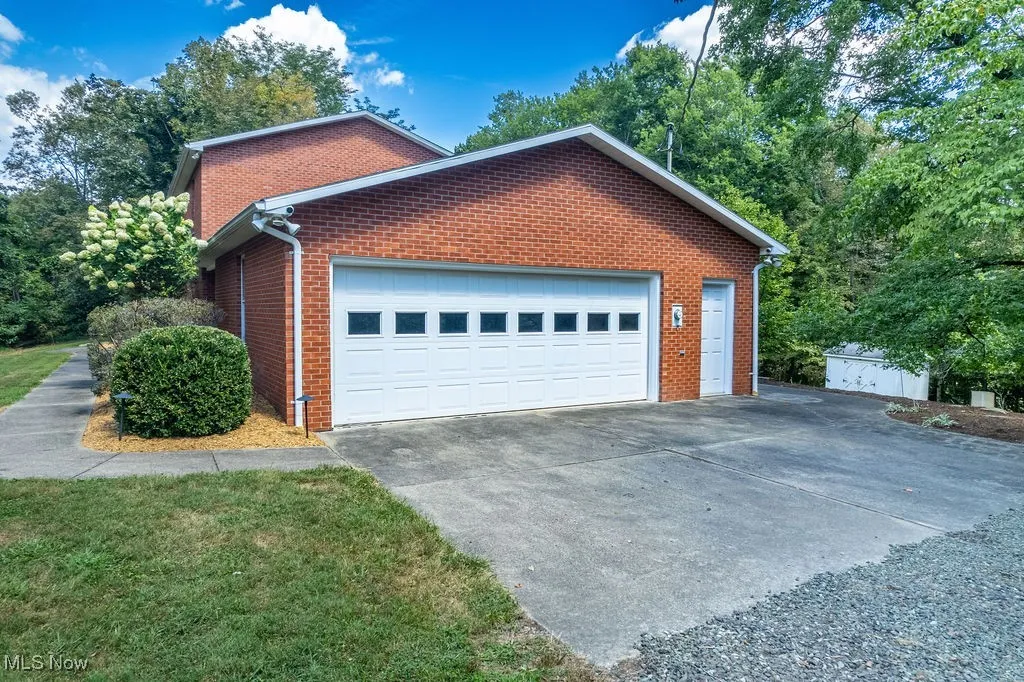 View of property exterior featuring brick siding, concrete driveway, and a garage