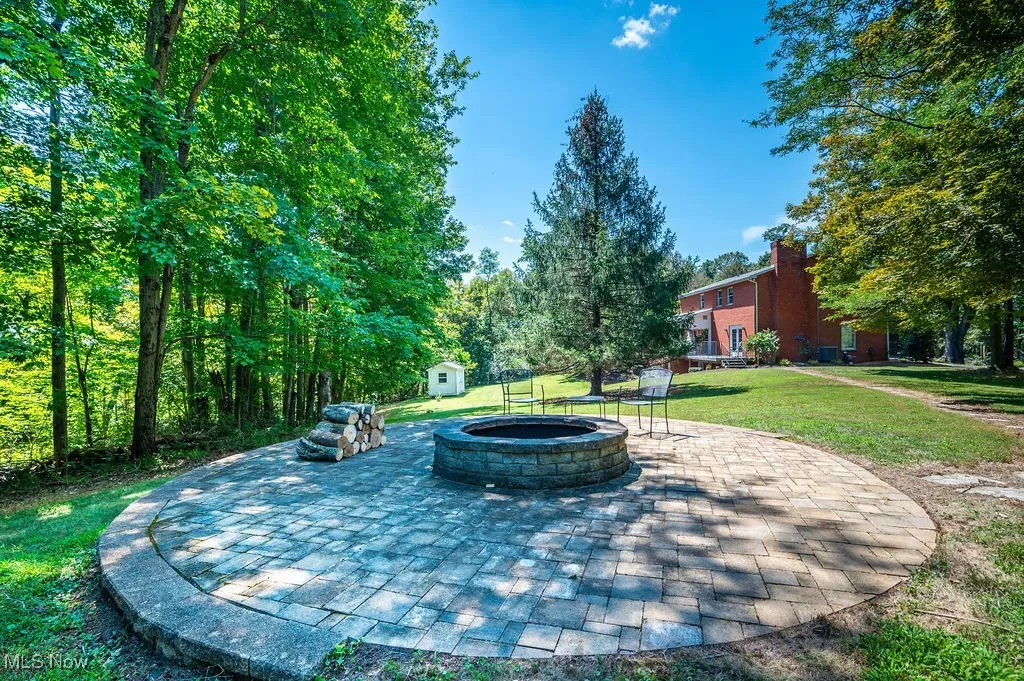 View of patio / terrace featuring an outdoor fire pit and a shed
