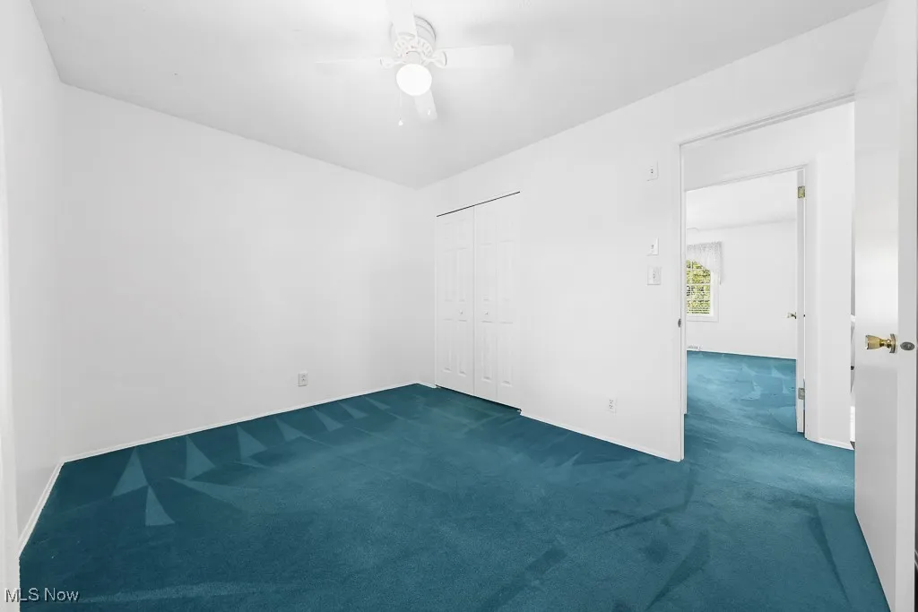 Spare room featuring dark colored carpet and ceiling fan