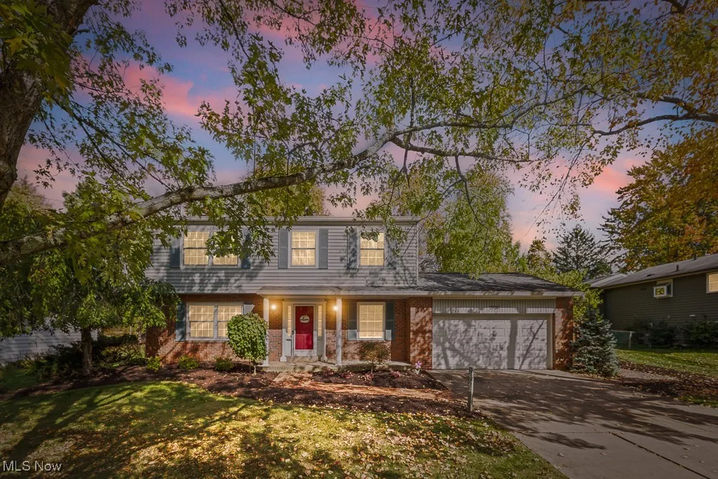 View of front of property featuring brick siding, a porch, concrete driveway, a garage, and a lawn