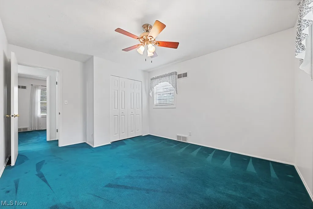 Unfurnished bedroom featuring carpet flooring, a ceiling fan, and a closet