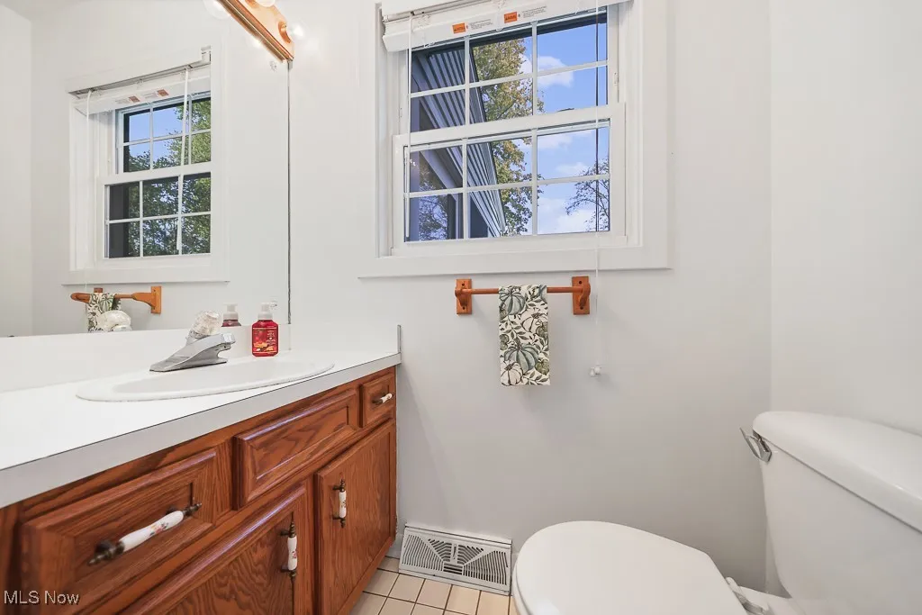 Half bathroom with plenty of natural light, vanity, and light tile patterned flooring