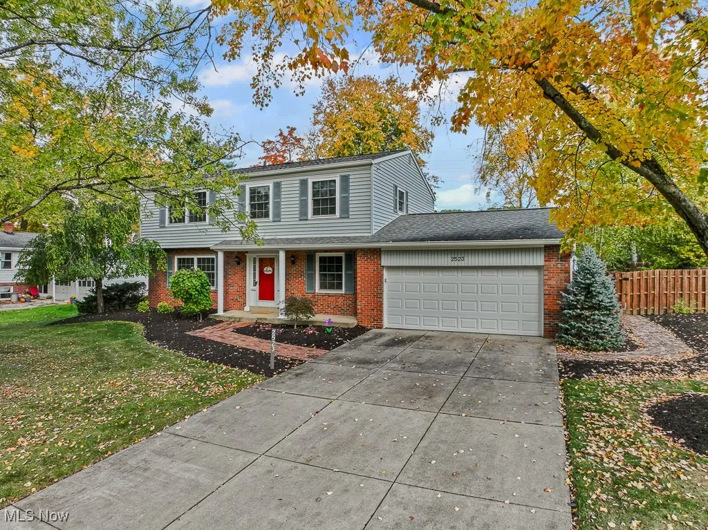 Traditional-style house with brick siding, an attached garage, and concrete driveway