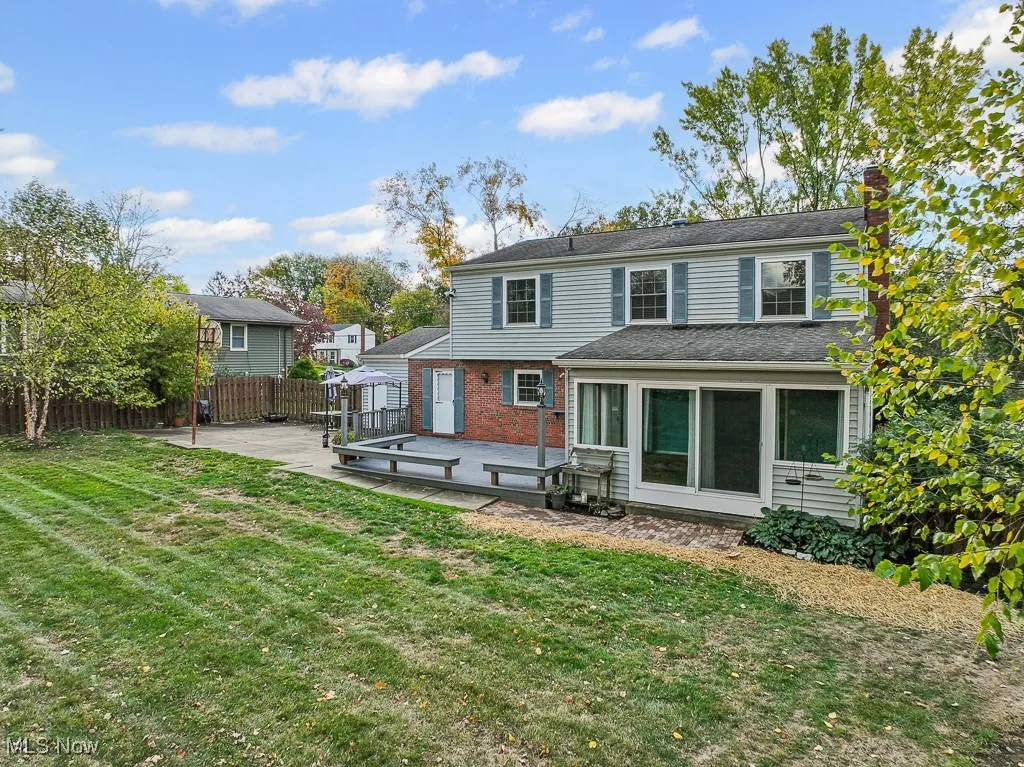 Rear view of property with a chimney, brick siding, a wooden deck, and a sunroom