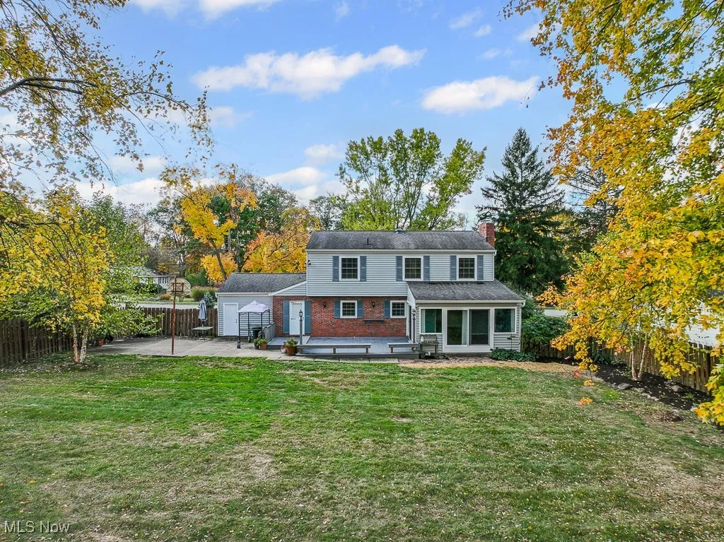 Back of house with a fenced backyard, a chimney, brick siding, a patio area, and a garage