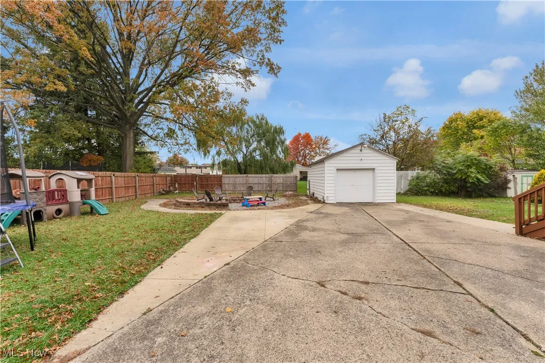 Fenced backyard featuring a trampoline, a playground, and a storage shed