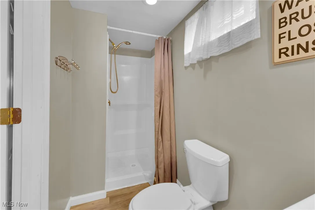 Bathroom featuring a shower stall and wood finished floors