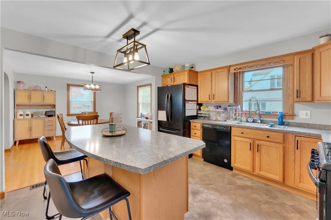 Kitchen featuring a kitchen breakfast bar, black appliances, a kitchen island, and healthy amount of natural light