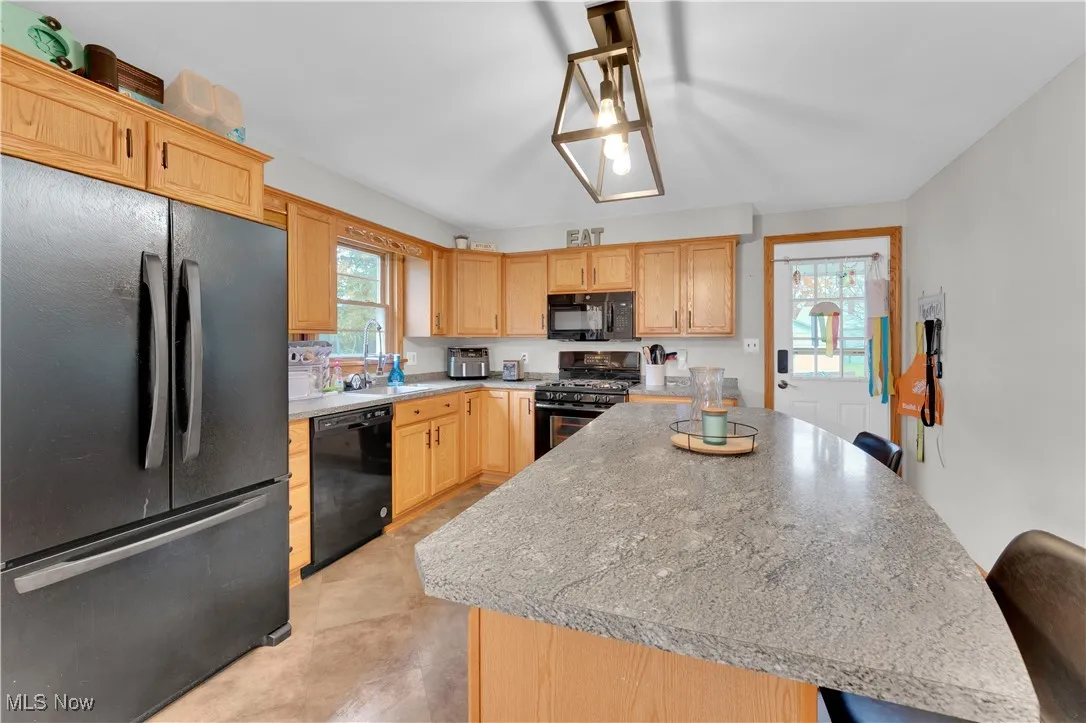 Kitchen with black appliances, a kitchen island, light countertops, and plenty of natural light