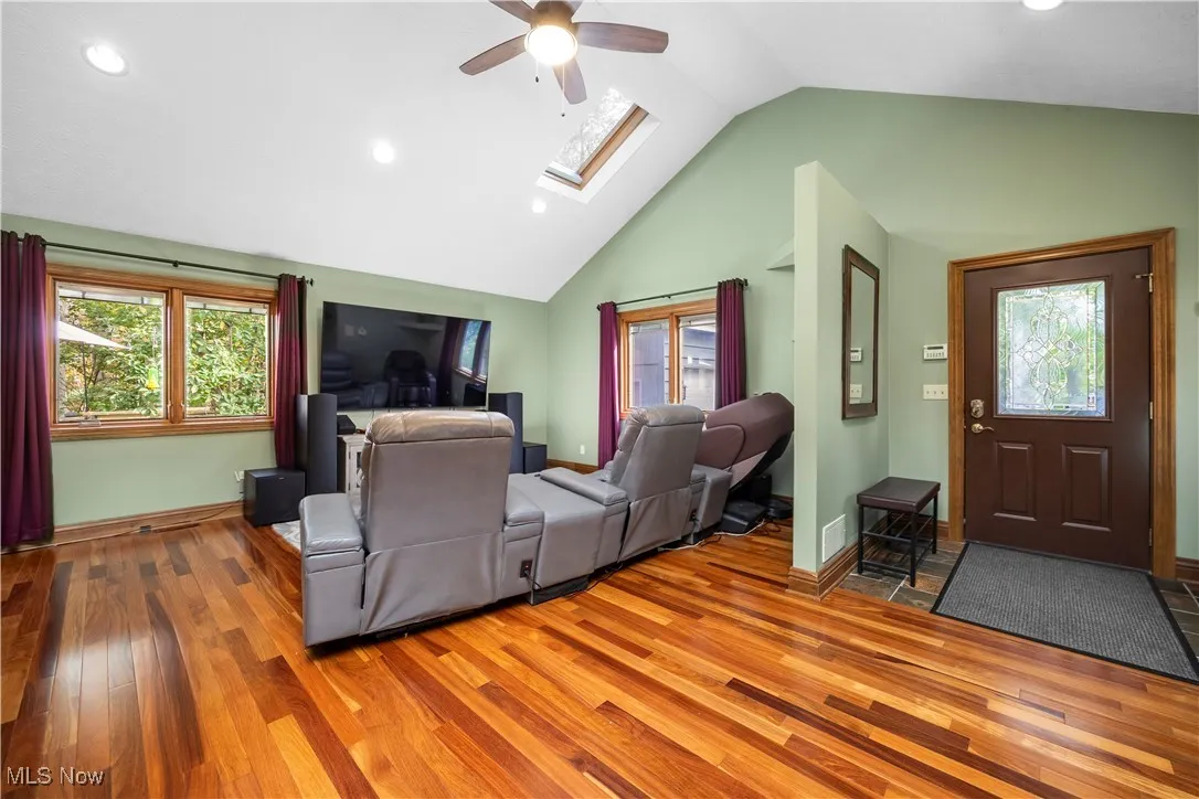 Living room featuring a skylight, recessed lighting, plenty of natural light, wood finished floors, and a ceiling fan