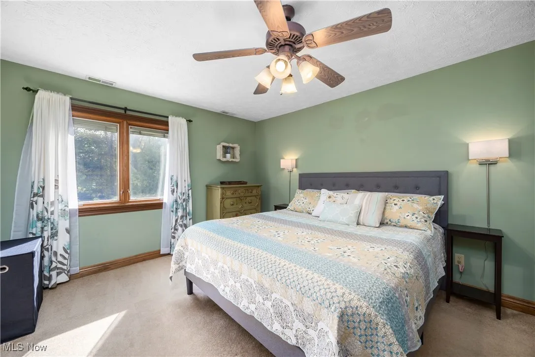 Carpeted bedroom featuring a textured ceiling and a ceiling fan