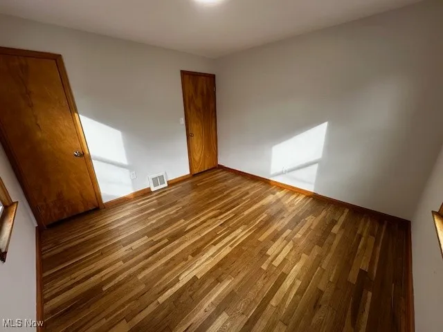 Unfurnished bedroom featuring wood finished floors and baseboards
