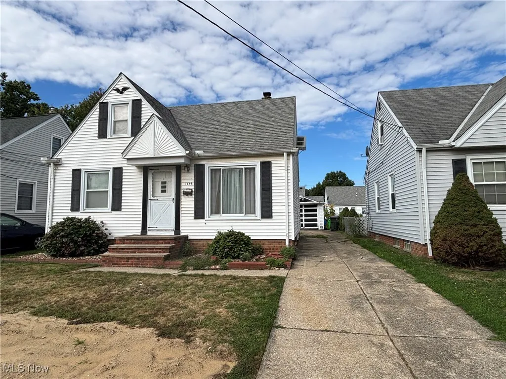 Bungalow with a shingled roof, a front yard, concrete driveway, and a chimney