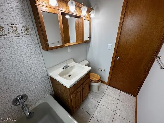 Bathroom featuring vanity, light tile patterned flooring, and shower / tub combination