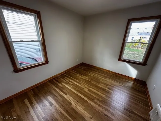 Empty room featuring baseboards and wood-type flooring