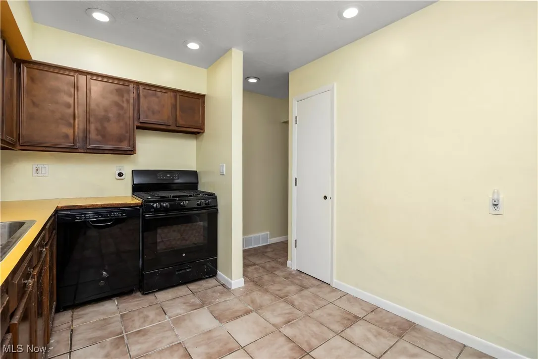 Kitchen featuring black appliances, dark brown cabinetry, light countertops, recessed lighting, and light tile patterned flooring