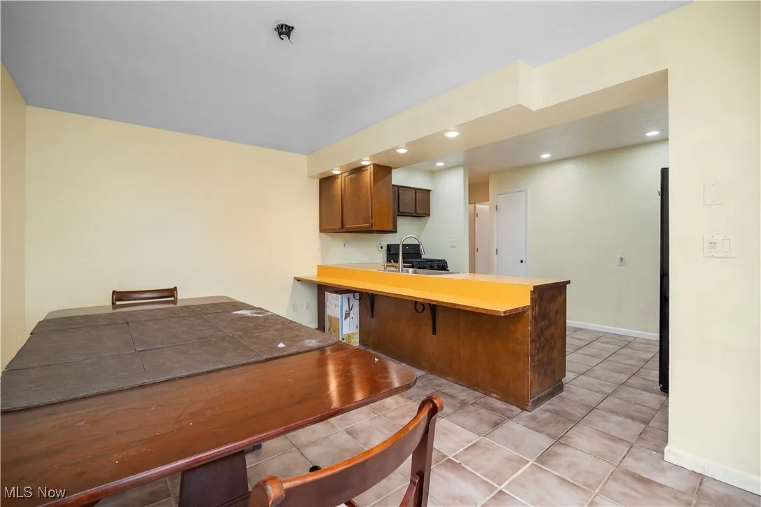 Kitchen with light countertops, a kitchen bar, a peninsula, light tile patterned floors, and recessed lighting