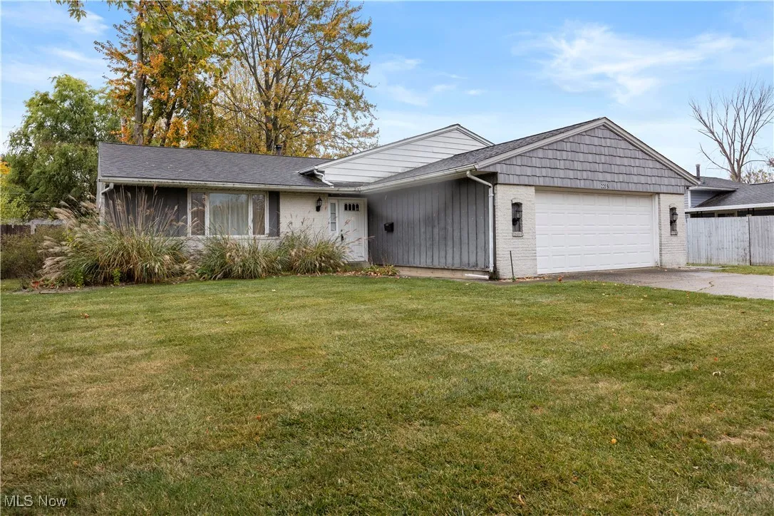 Split level home featuring a front yard, brick siding, concrete driveway, and a garage