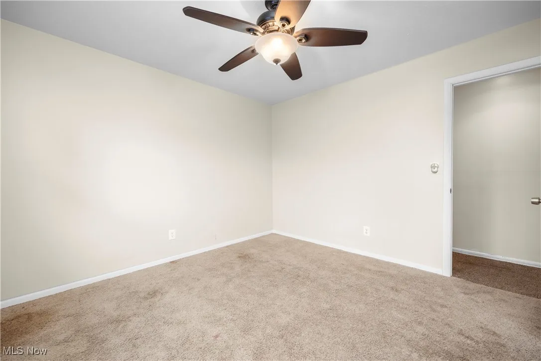 Carpeted spare room featuring baseboards and a ceiling fan