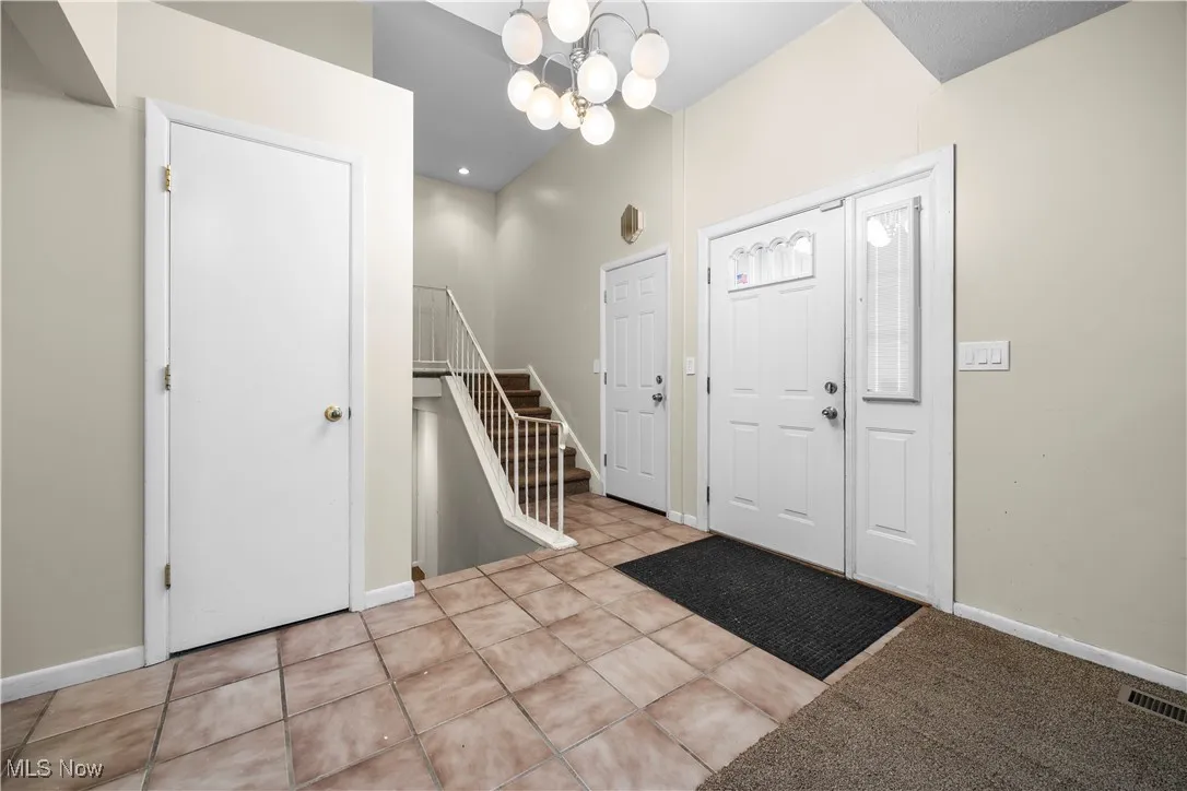 Tiled foyer featuring a chandelier and stairs