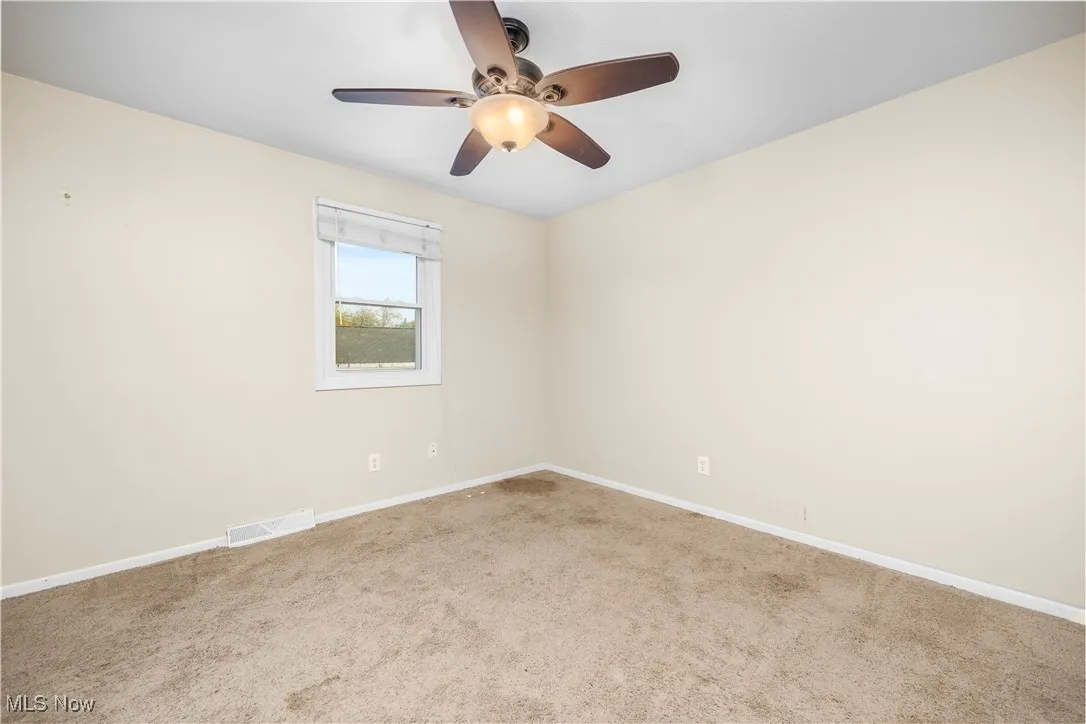 Carpeted empty room featuring baseboards and ceiling fan
