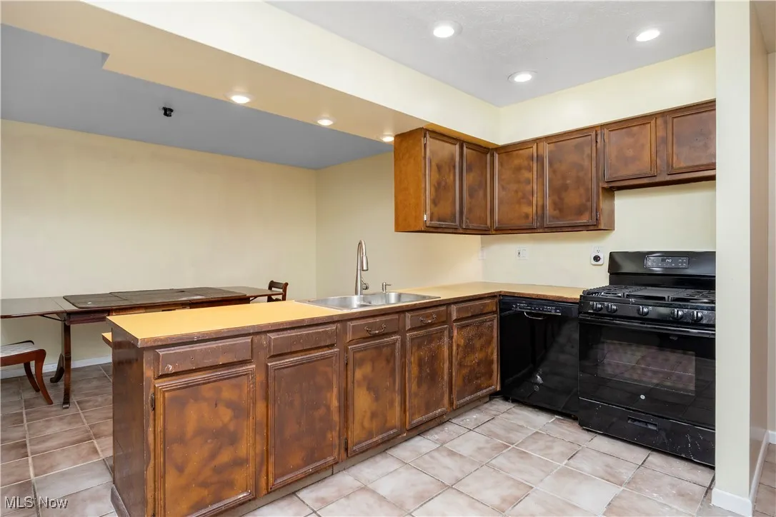 Kitchen with black appliances, a peninsula, recessed lighting, light countertops, and light tile patterned floors
