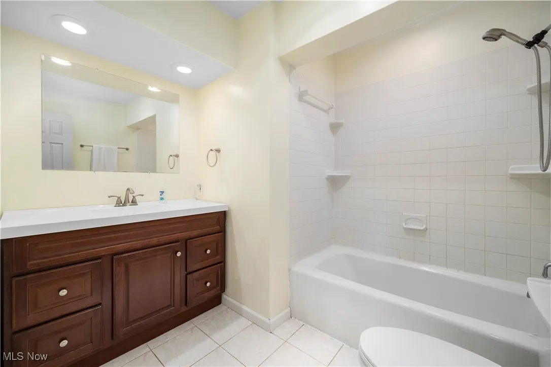 Bathroom featuring vanity, light tile patterned floors, and  shower combination