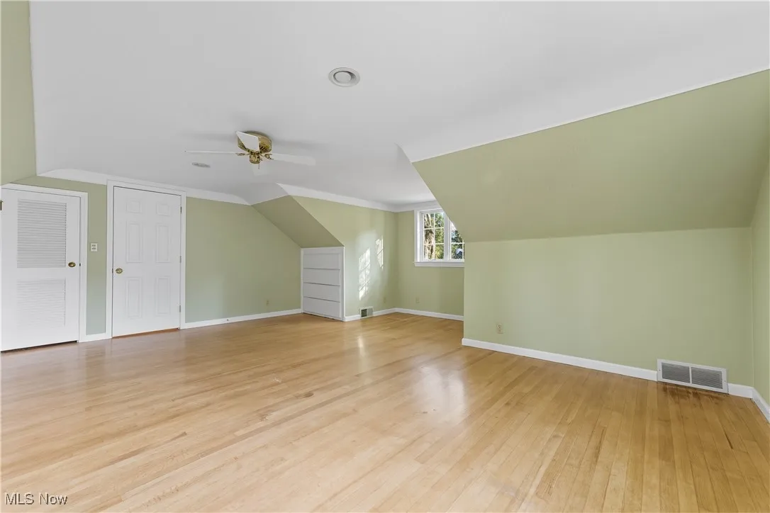 Bonus room featuring light wood-style flooring, lofted ceiling, and ceiling fan