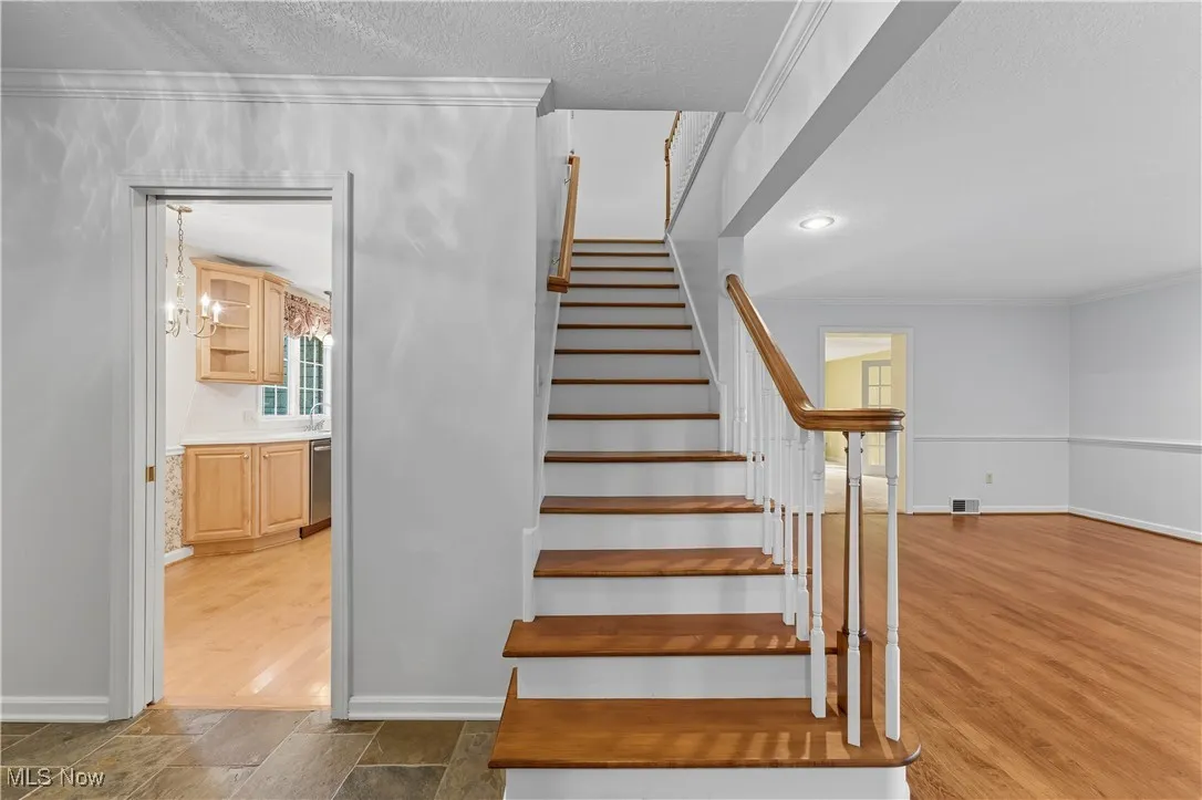 Staircase featuring ornamental molding, a textured ceiling, and a chandelier