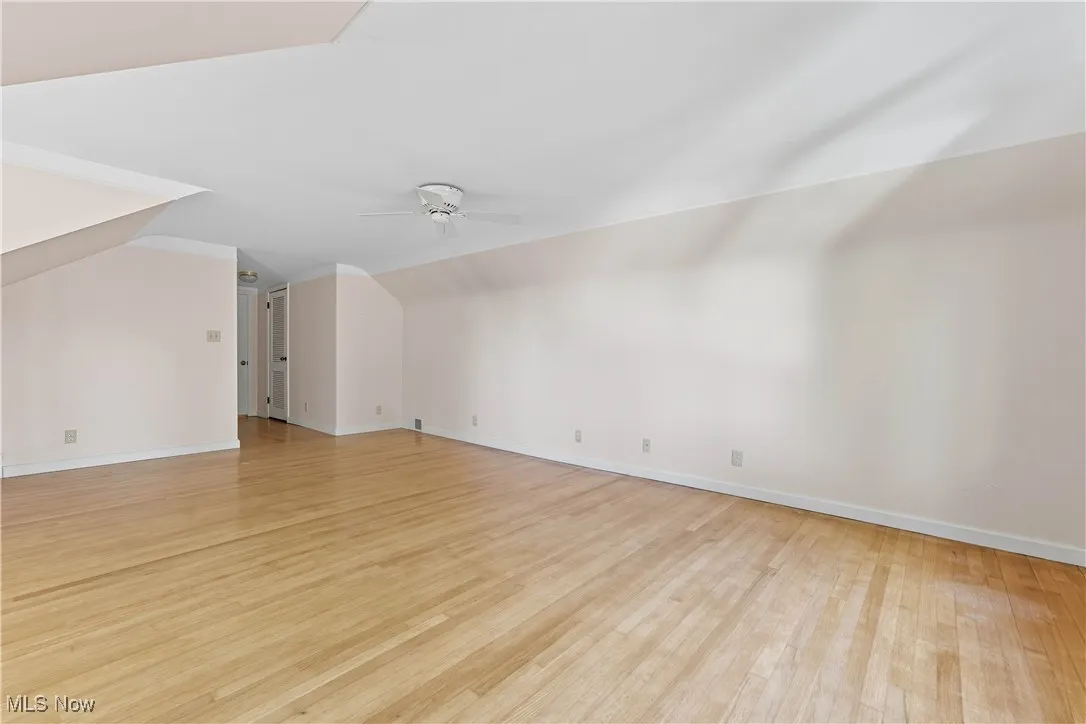 Unfurnished living room featuring light wood-style floors, vaulted ceiling, and a ceiling fan