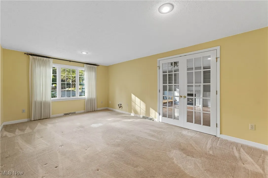 Unfurnished room with light carpet, french doors, a textured ceiling, and recessed lighting