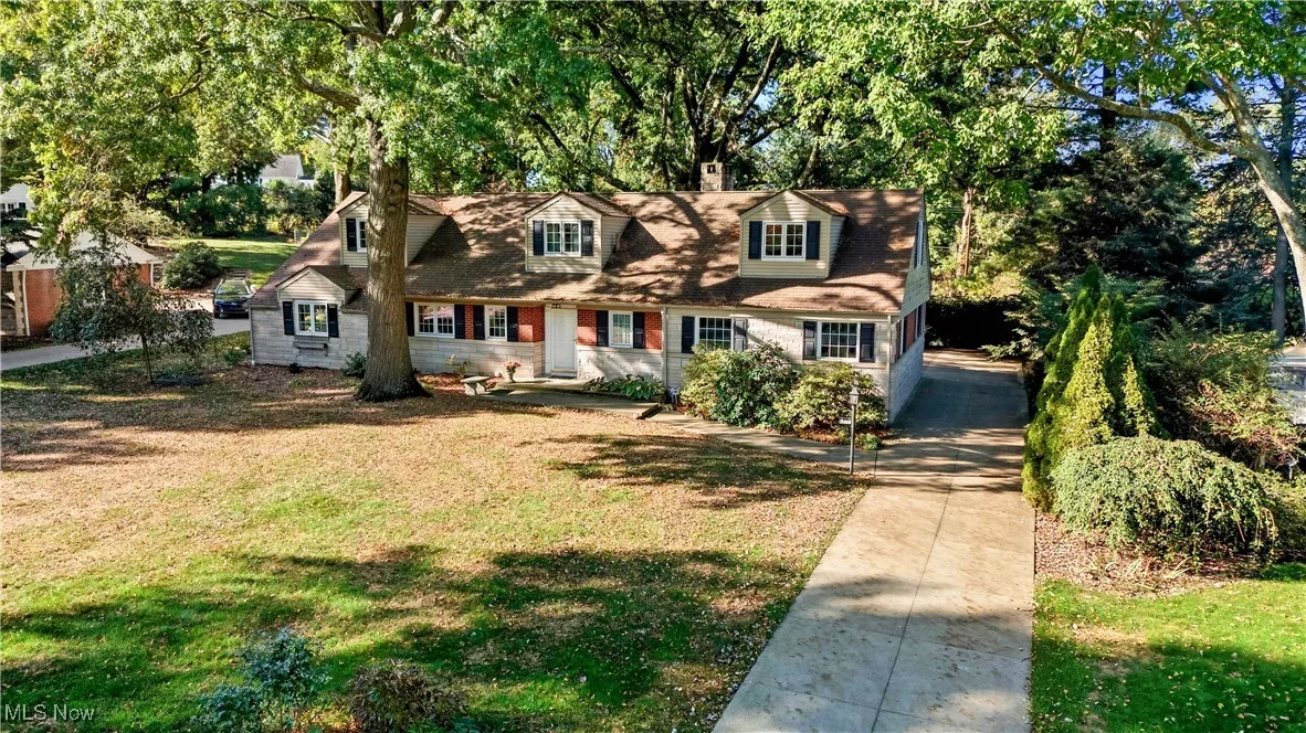 Cape cod house with a front lawn and view of scattered trees