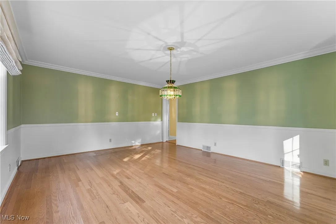 Empty room with ornamental molding and light wood finished floors
