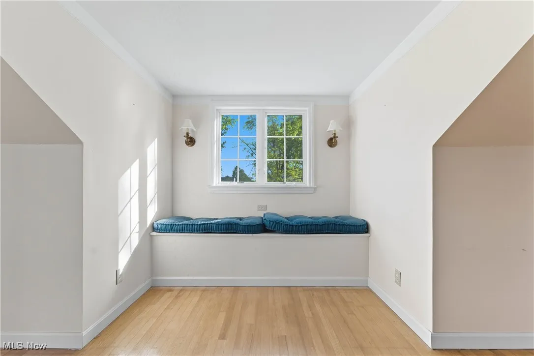 Living area with light wood-type flooring and crown molding