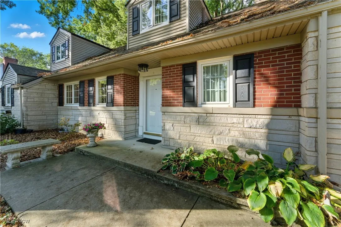 Property entrance with brick siding, covered porch, and stone siding